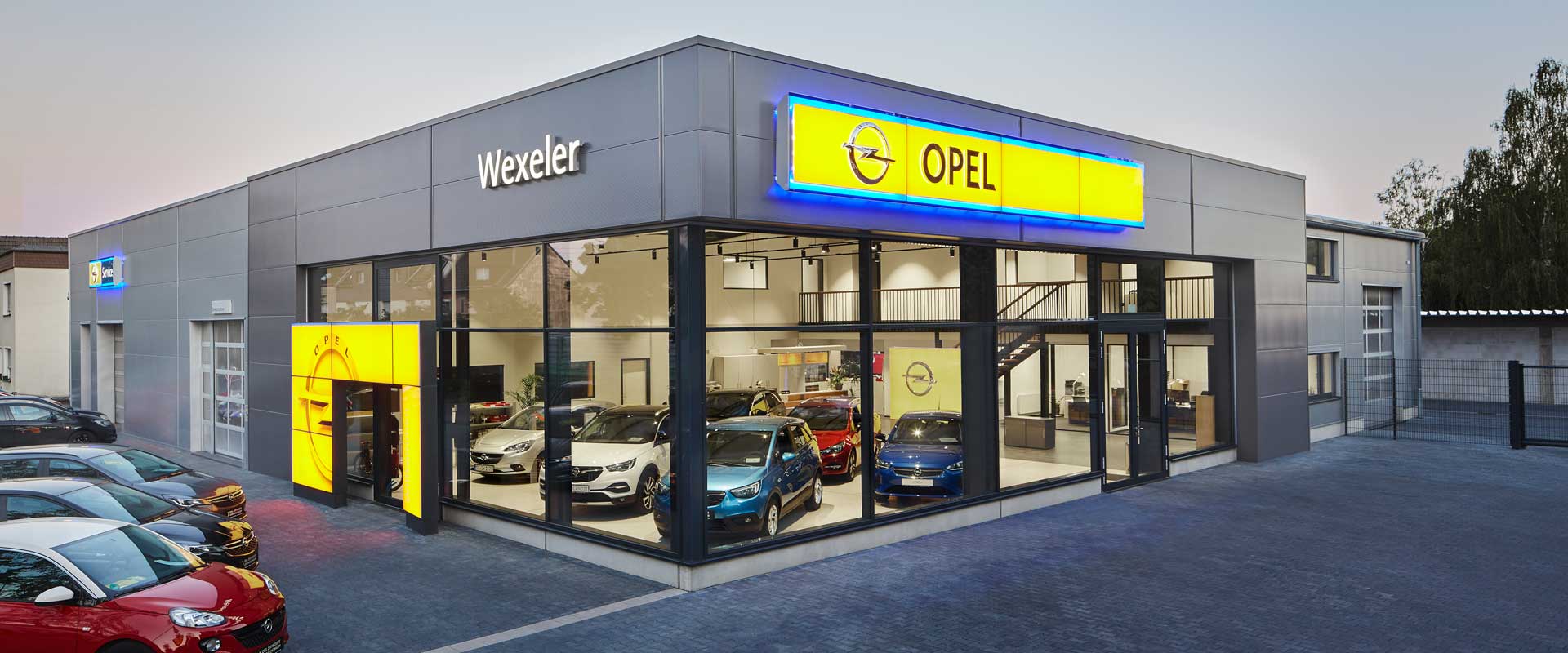 Exterior view with a view into the sales room and the exhibition of vehicles.