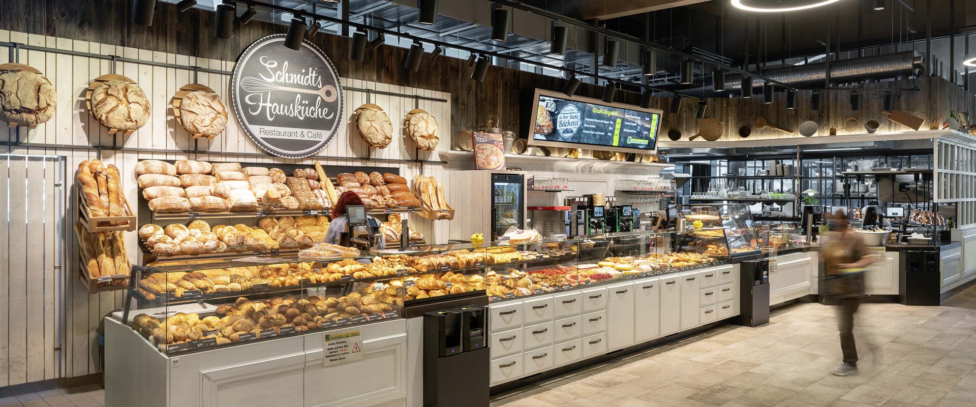 Fresh food counter for baked goods, illuminated with the Canilo spotlight, with a view towards the catering area.