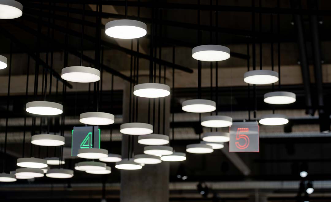 Detailed view of the installation with suspended Much Moon luminaires over the checkout area. 