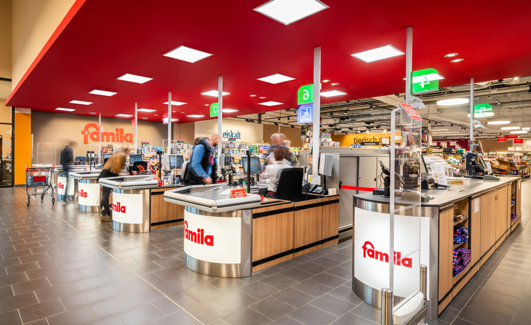 Human centric lighting in the checkout area at Famila Trittau – in the evening with a warm lighting mood matching the daylight. 