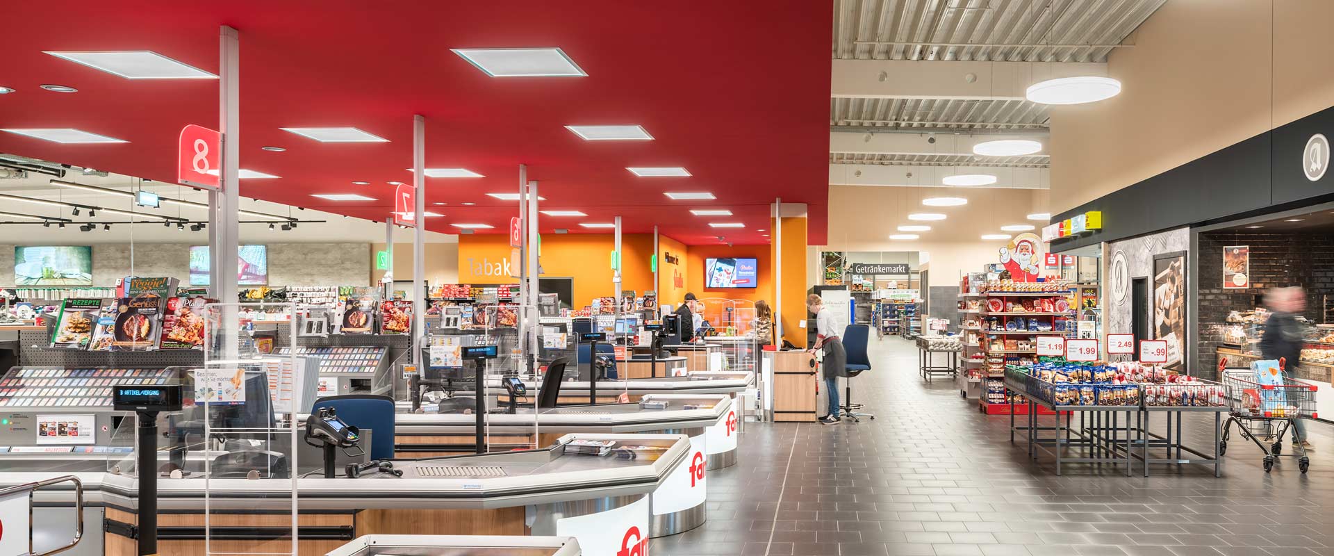 Area casse e corridoio di negozi esterno al supermercato illuminati con Arimo Active e Solegra. 