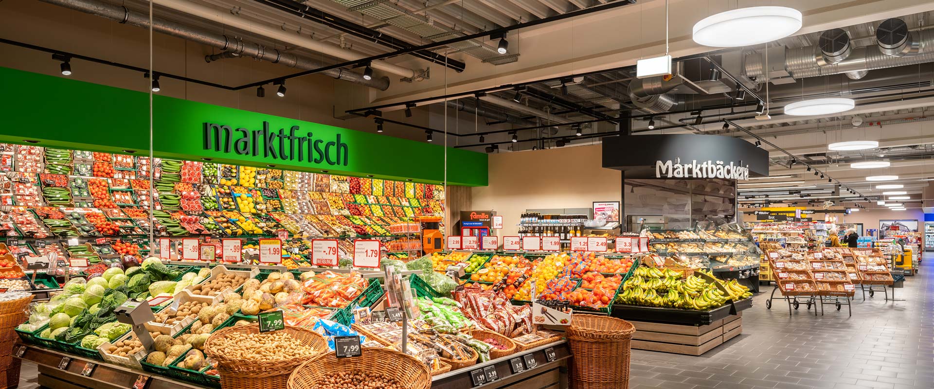 Obst und Gemüse Abteilung mit Blick in den Hauptgang beleuchtet mit Strahler B.VEO und Pendelleuchte Solegra.